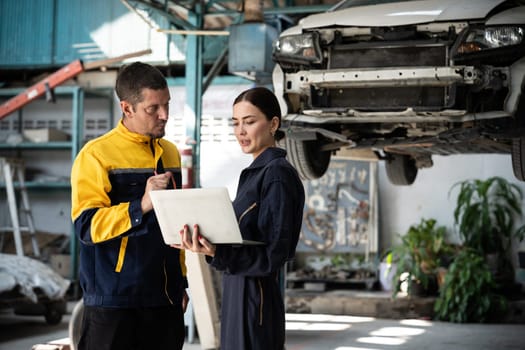 Two vehicle mechanic working together, conduct car inspection with laptop. Automotive service technician in uniform carefully make diagnostic troubleshooting to identify error. oxus