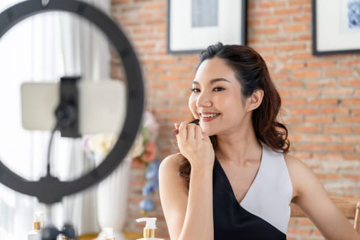 Asian Woman influencer shoot live streaming vlog video review makeup uttermost social media or blog. Happy young girl with cosmetics studio lighting for marketing recording session broadcasting online