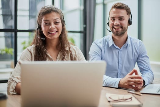 Attractive man and charming woman are sitting at laptops in headphones