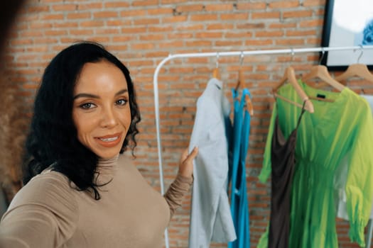 Woman influencer shoot live streaming vlog video review clothes crucial social media or blog. Happy young girl with apparel studio lighting for marketing recording session broadcasting online.