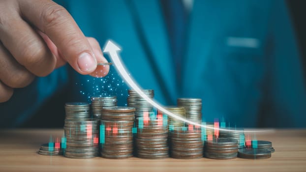 Businessman puts money on pile of coins. Ideas for investing and growing a business, maximizing profits from business, ideas for setting savings goals and setting goals for fixed deposits with banks.