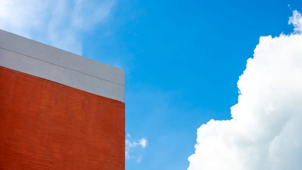 Orange building on a background of sky and white clouds.