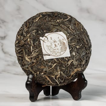A beautifully stunning puerh tea cake that is artfully displayed and presented on a lovely wooden stand