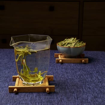 A peaceful scene with a beaker of green tea leaves beside a bowl of aromatic tea, creating a tranquil vibe