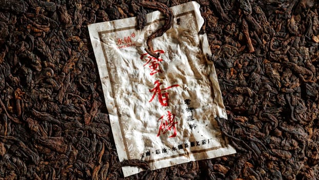 A closeup view of a faded and worn Chinese package resting on dark, rich soil, showcasing its wear and age beautifully
