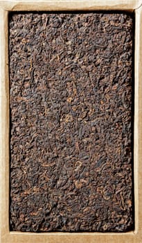 A closeup view of a dense black tea leaf cake, beautifully highlighting its rich texture and earthy tones