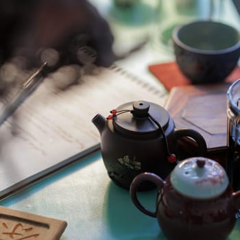 A delightful and serene setup featuring beautiful teapots along with a notepad, perfect for enjoying a tea ceremony
