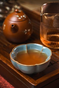 An aesthetically pleasing tea setup that includes a teapot, a cup, and warm tea elegantly displayed on a wooden tray