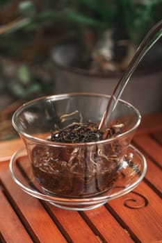 A delightful cup of freshly brewed herbal tea, artfully steeped in a clear glass cup, accompanied by a silver spoon