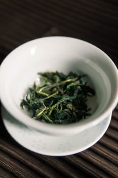 A soothing bowl of dried green tea leaves, beautifully prepared for brewing, showcasing its natural vibrancy