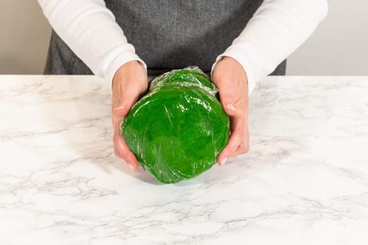 Stack of vibrant green dough discs wrapped in plastic, prepared for chilling in Vibrant Green Gingerbread Cookies for Festive Baking. These dough discs will be chilled and then rolled for cookie shaping.