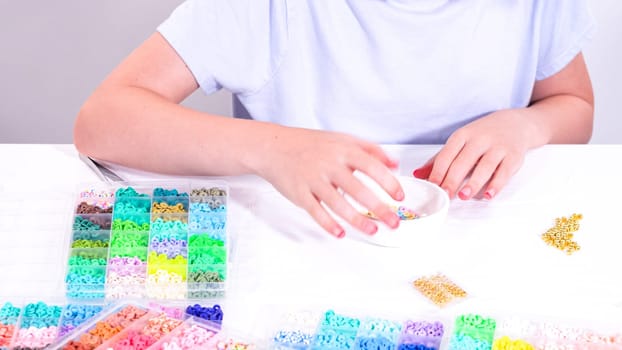 Delicate fingers of a young girl navigate through a treasure trove of bright, multicolored beads, each compartment revealing a new hue to choose from.