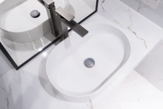 Chrome water faucet and white pedestal sink in bathroom . Stylish bathroom.