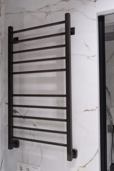 Modern black radiator on white marble wall in bathroom. New bathroom with granite white tiles.