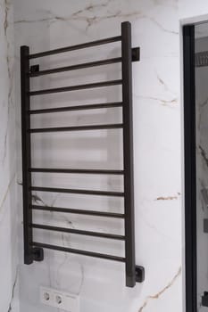 Modern black radiator on white marble wall in bathroom. New bathroom with granite white tiles.