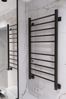 Modern black radiator on white marble wall in bathroom. New bathroom with granite white tiles.