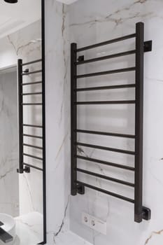 Modern black radiator on white marble wall in bathroom. New bathroom with granite white tiles.