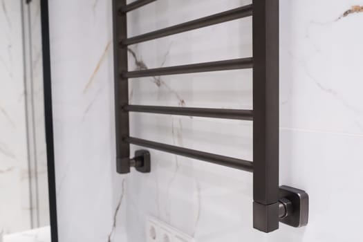 Modern black radiator on white marble wall in bathroom. New bathroom with granite white tiles.