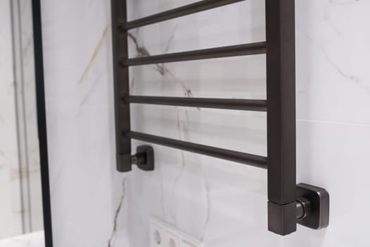 Modern black radiator on white marble wall in bathroom. New bathroom with granite white tiles.