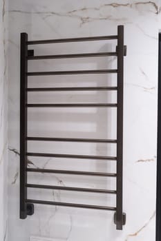 Modern black radiator on white marble wall in bathroom. New bathroom with granite white tiles.