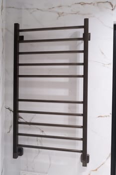 Modern black radiator on white marble wall in bathroom. New bathroom with granite white tiles.