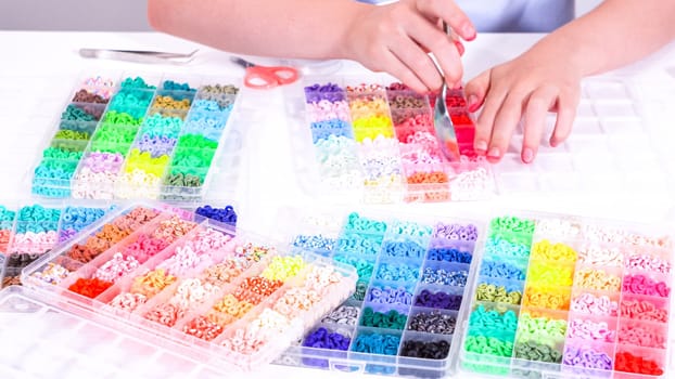 Delicate fingers of a young girl navigate through a treasure trove of bright, multicolored beads, each compartment revealing a new hue to choose from.