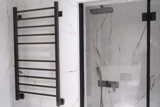 Modern black radiator on white marble wall in bathroom. New bathroom with granite white tiles.