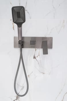New stylish faucet and shower in shower enclosure with white granite walls. Modern luxury shower cubicle.