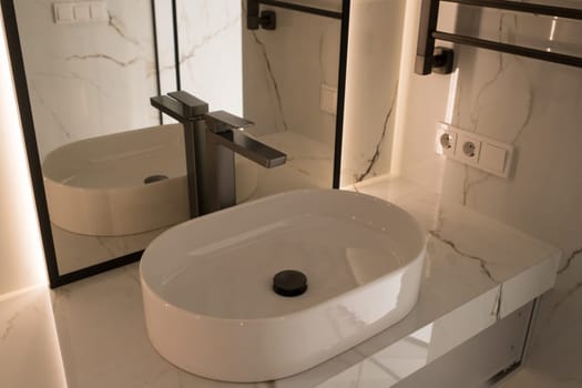 Chrome water faucet and white pedestal sink in bathroom . Stylish bathroom.