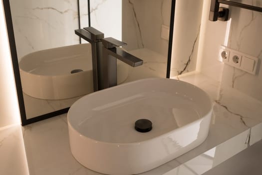 Chrome water faucet and white pedestal sink in bathroom . Stylish bathroom.