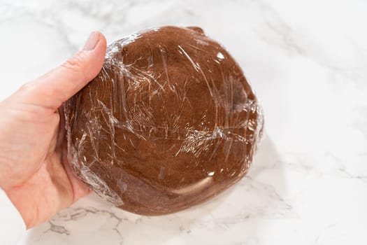 Stacked discs of Chocolate Ginger Sugar Cookie Dough wrapped in plastic, ready to chill, showing a smooth and uniform dough texture.