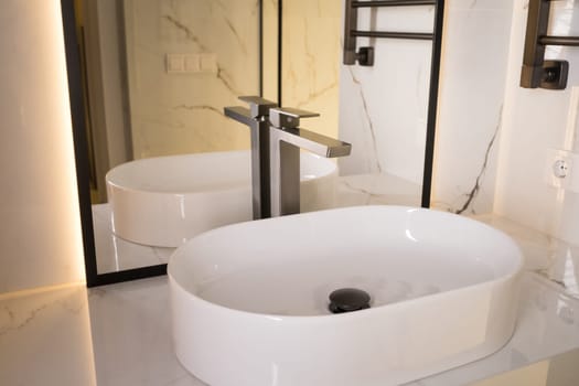 Chrome water faucet and white pedestal sink in bathroom . Stylish bathroom.