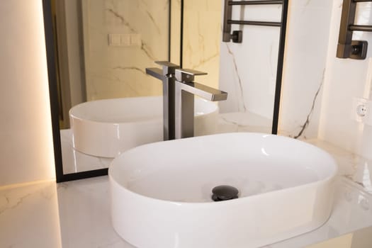 Stylish deluxe water faucet and white countertop sink in bathroom. Stylish bathroom.