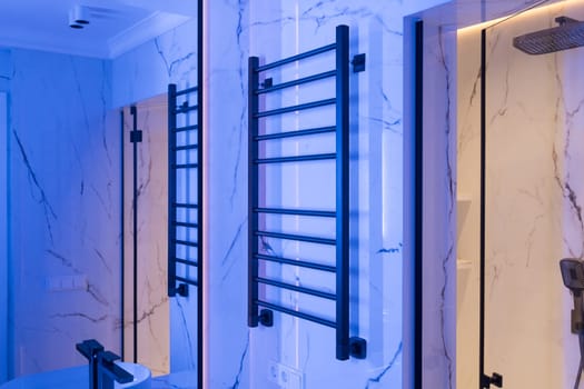 Modern black radiator on white marble wall in bathroom. New bathroom with granite white tiles.