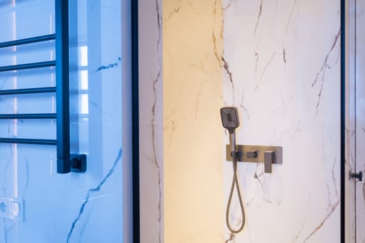 New stylish faucet and shower in shower enclosure with white granite walls. Modern luxury shower cubicle.