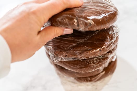 Multiple wrapped dough disks stacked, ready for refrigeration, setting up for batch baking later.