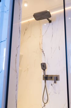 New stylish faucet and shower in shower enclosure with white granite walls. Modern luxury shower cubicle.
