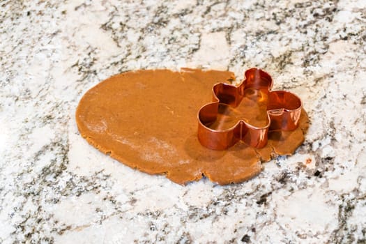 In a contemporary white kitchen, gingerbread cookie dough is skillfully rolled out, setting the stage for a delightful holiday treat.