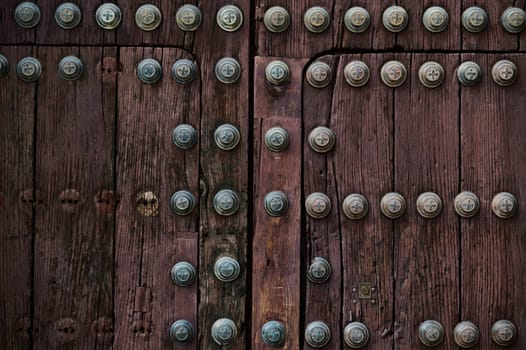 Detailed image of a wooden medieval door with decorative metal studs, showing rich texture and craftsmanship.