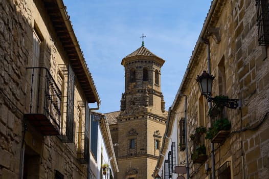 Scenic view of ancient stone architecture featuring a historic tower amidst rustic buildings under a clear sky.