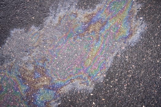 Circular patch of vibrant gasoline or oil spill on the roadway