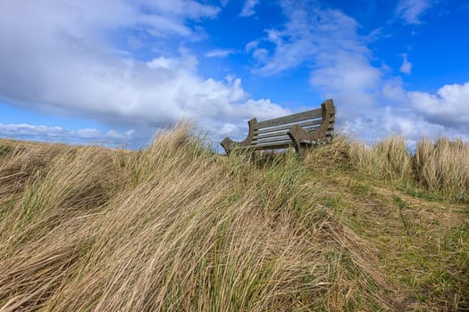 A park bench under a partly cloudy sky on Del Ray beach in Seaside, Oregon.