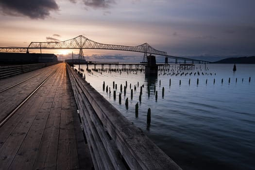 A wooden walkway leads towards the landmark Astoria-Megler bridge in Astoria, Oregon.