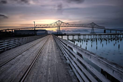 A wooden walkway leads towards the landmark Astoria-Megler bridge in Astoria, Oregon.