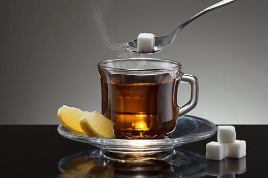Putting a sugar cube into a cup of hot tea.