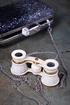 Vintage opera glasses with a black clutch are elegantly displayed. Image evokes nostalgia and luxury