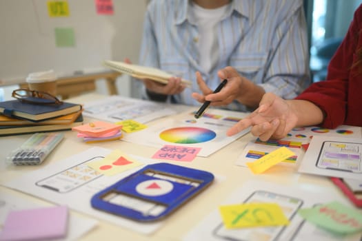 Close up of young designers collaborating on design project at office. Technology and app development concept.