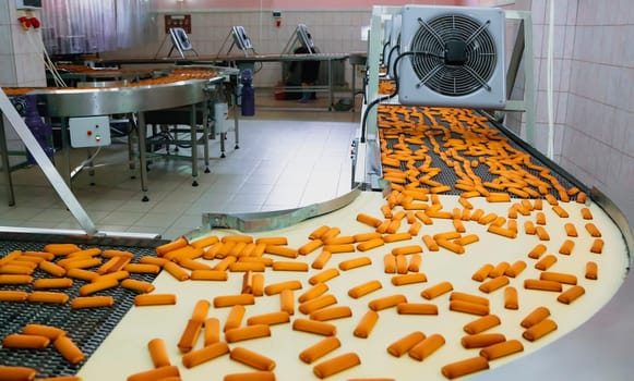 In a bustling confectionery factory, a production line efficiently moves freshly baked cookies. Staff monitor the process while ensuring quality control in an organized setting.