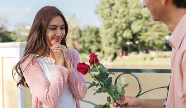 A romantic moment unfolds as a couple shares a heartfelt exchange of roses by the river celebrating love on Valentine Day.