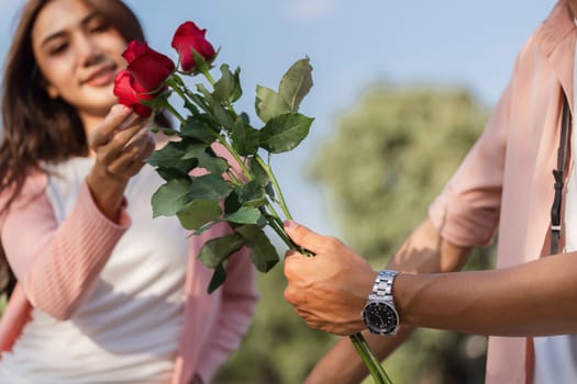 A couple exchanges roses symbolizing love and affection on Valentine's Day amidst a beautiful park setting.